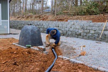 Garaj yolu çakıllarla kaplı olan otoparka yağmur suyu için drenaj borusu döşemek gerekiyor.