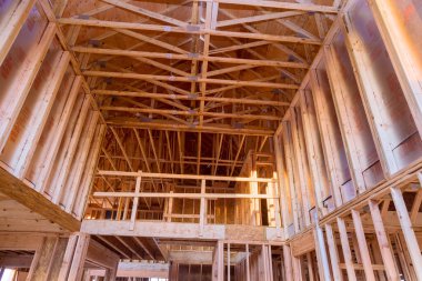 Standart ahşap çerçeveli bina, çatıya yakın, kirişleri çivileyen işçiler.