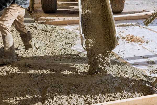 Бетономешалка заливает бетон на строительную площадку вокруг недавно построенного дома, так что он может сделать тротуар