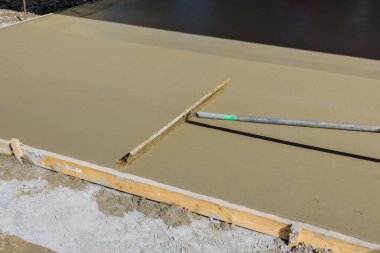 When construction worker uses broom to brush fresh wet concrete result will be groove texture pattern that appears on surface