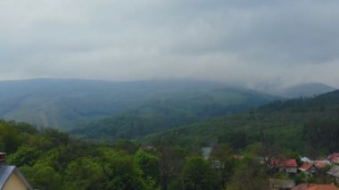 Scene of peaceful morning in mountains is full of forest and fog above small village