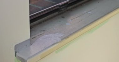 Repairman painting in painting window molding trim using paintbrush with renovation apartment