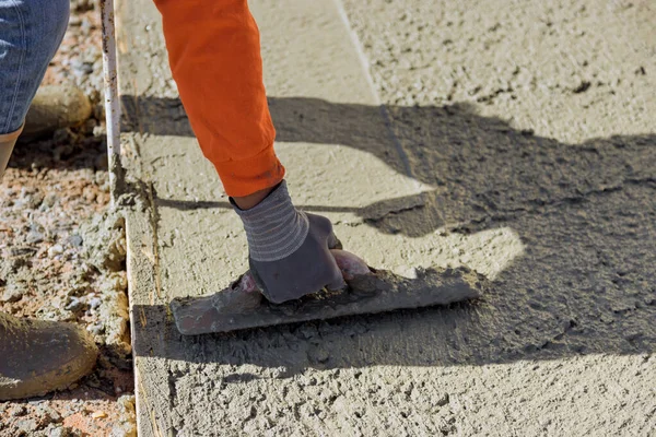 After pouring concrete worker uses trowel to plaster wet concrete cement floor