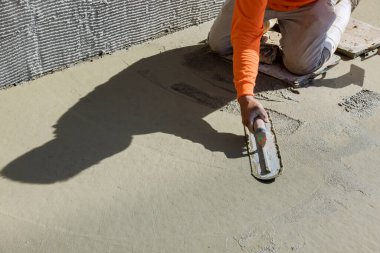 Plastering wet cement concrete floors with use of trowel after concrete has been poured