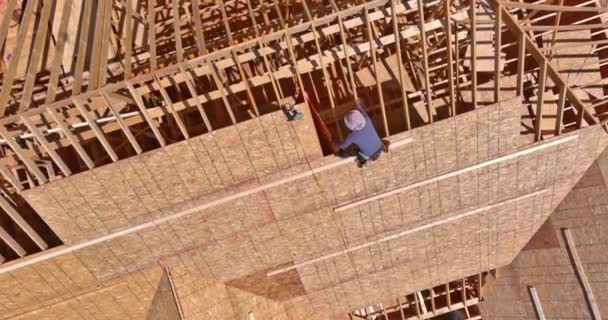屋根の上で働く請負業者によって合板で未完成の家の屋根が設置されている — ストック動画