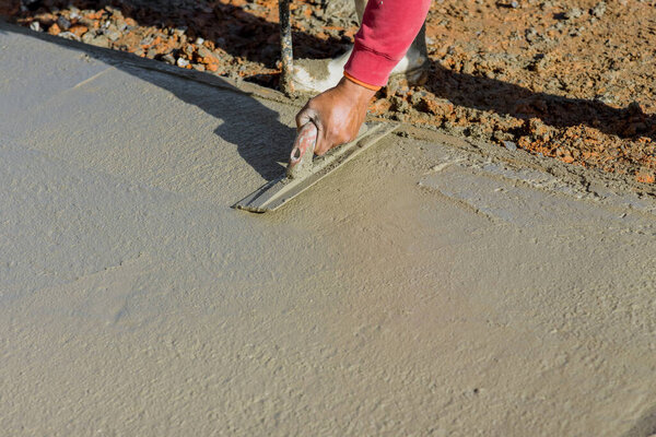 Рабочий штукатурка мокрый бетонный пол с помощью лопатки после заливки бетона