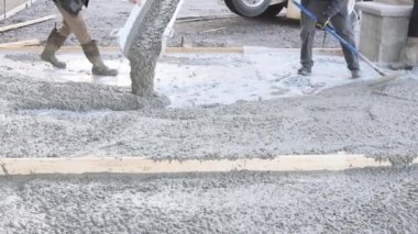 Concrete mixing truck pours out concrete for pavement surrounding new home