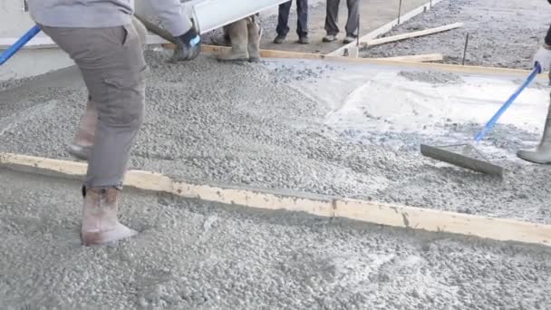 인부가 시멘트 보도에 흙손을 사용하여 콘크리트를 바닥에 박았다 — 비디오