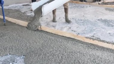 An concrete mixing truck pour out concrete for pavement around new house