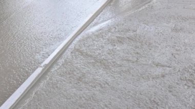 Concrete was poured on wet cement sidewalk by construction worker to level concrete as it was poured.