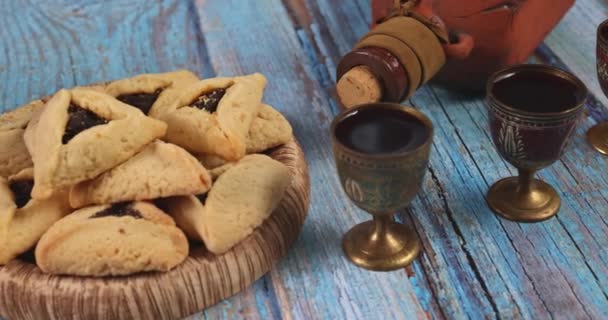 プリム祭りはクッキーで祝われるユダヤ教の宗教祭です音作りのノイズメーカーの高いカーニバルマスクとお祝いのシンボルとしてHamantaschens — ストック動画