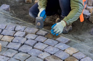 Sound of workers hammering granite stones into place echoed through streets as they paved pavement with industrial cobblestones