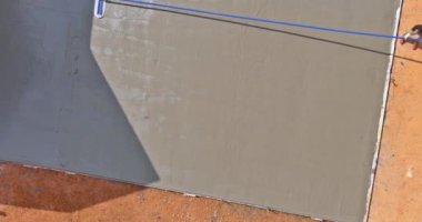 After pouring concrete over wet concrete surface worker plasters floor with trowel using