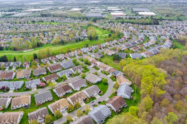 View of small American town residential complex district with houses and roads on an aerial view with spring trees