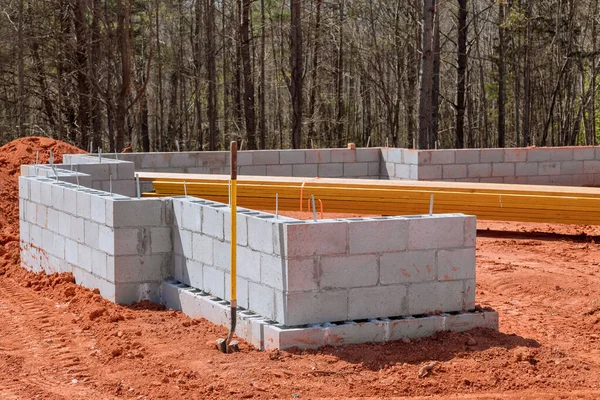 Cement block wall is constructed on construction site to support foundation of house.