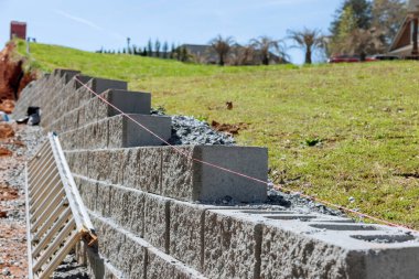 Building retaining wall that is being built on property near new home as part of building new home clipart