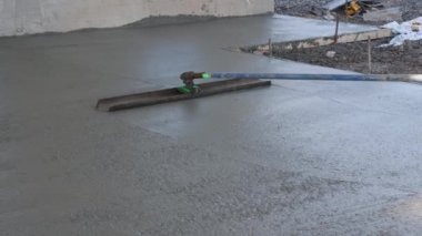 Worker was pouring concrete sidewalk using long trowel on wet cement surface he was leveling