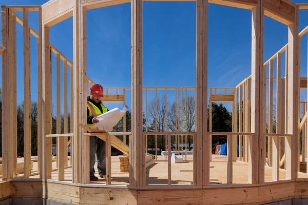 stock image In construction process an architectural engineer checks quality of work on site using construction blueprints