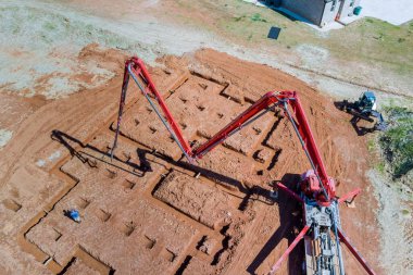 Beton pompa kullanarak inşaat işçisi evin temellerine beton döküyor.