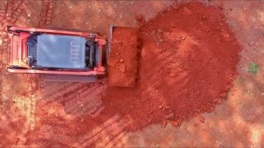Small tractor working with earth moving to land leveling in construction site near new house