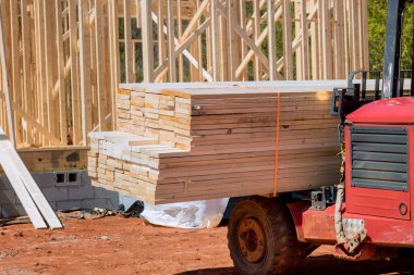 İnşaat alanında asansör manipülatörü teslim edilen ahşap yapı malzemelerini boşaltır.