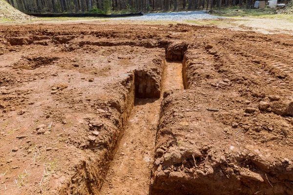 Building cement strip foundation fornew home digging trenches for pouring concrete under structure during construction