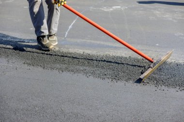 İnşaat işçileri sürecin ortasına asfalt yollar döşüyorlar.