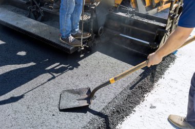 Yol yapım çalışmaları sırasında asfalt kaldırım makinesi ve buharlı yol silindiri, yeni yol katman süreci yerleştiriliyor