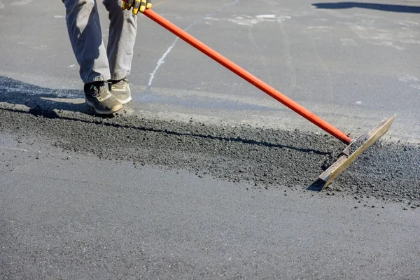 Construction workers laying new asphalt roads in middle of process asphalting