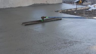 Worker was pouring concrete sidewalk using long trowel on wet cement surface he was leveling