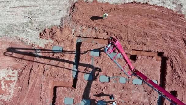 労働者が自動ポンプを使用して建物の基礎のためのコンクリートを注ぐように指示されている — ストック動画