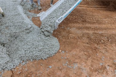 Beton inşaat müteahhitleri garaj yolu dökerken ıslak beton dökerek çalışıyorlar.