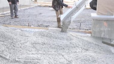 Mixing concrete truck pours concrete for pavement surrounding newly constructed house on building site