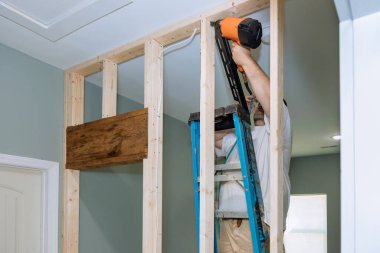 Havalı çekiç, inşaatçılar tarafından konut iskeletine tahta kirişler çakmak için kullanılıyor.