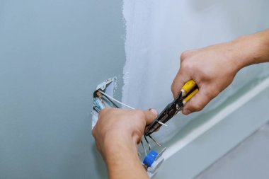 Elektrikçi, yeni ev inşaatında güvenli şekilde çalışan yeni bir soket kuruyor