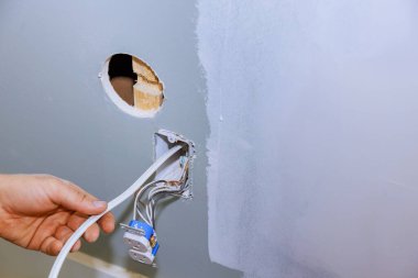 Yeni ev inşaatının yapıldığı yere güvenli bir şekilde çalışan bir elektrikçi tarafından yeni bir soket takıldı