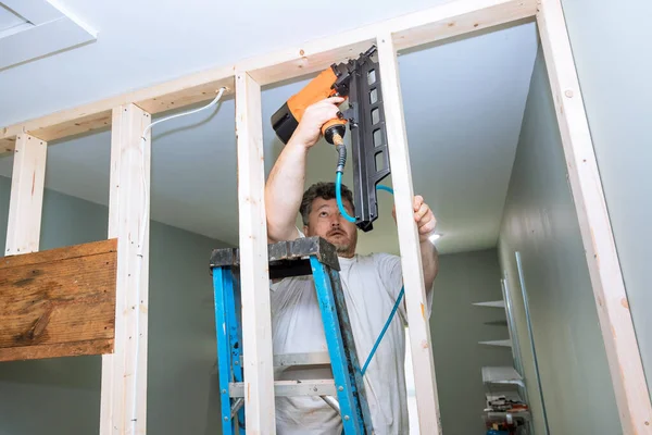 建築家は家の建設のための木製の梁のフレームワークを釘に空気ハンマーを使用します — ストック写真