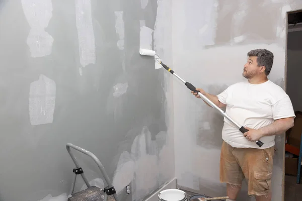 stock image Update improvement for an apartment room during repair process, master painting walls with roller white paint