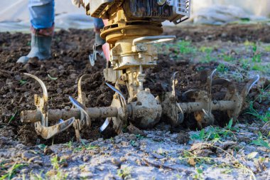 Çiftçi bahçesinde, motorlu ekicinin dümen bloğuyla toprağı sürmüş..