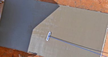 On wet cement sidewalk construction worker use long trowel to level concrete he was pouring
