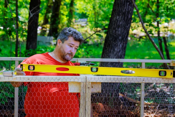 stock image Using level worker levelling new wooden domestic chicken coop on farm build containing metal mesh