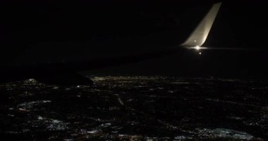 Gece gökyüzünde sessizce süzülen uçak, şehrin parıldayan ışıklarının üzerinden geçiyordu..