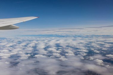 Uçak penceresi büyüleyici Dünya manzarası ile büyülenmiş bulutlu gökyüzünün engin manzaraları..