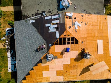 During repair work on apartment buildings roof old shingles were replaced plywood and new shingles were installed. clipart