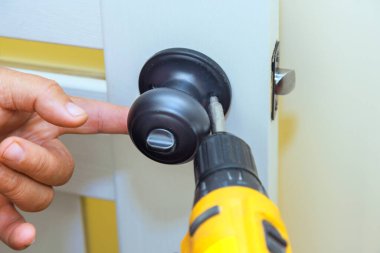 İşçi tornavida kullanarak yeni iç kapıya kilit takıyor