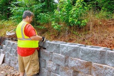 Çalışan inşaat işçisi, istinat duvarına beton blok yapıştırdı