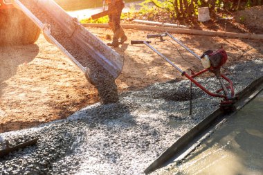 Karıştırıcı kamyonu ıslak çimento olan evin yakınındaki garaj yolu için hazır beton döküyor.