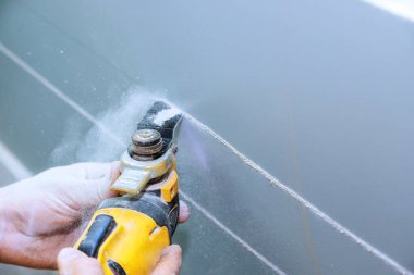 Duvara elektrik kablosu monte etmek amacıyla, sıva tahtası çoklu araç kullanılarak kesildi