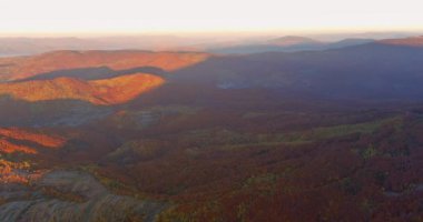 Misty fog descending upon Carpathians mountain valley creates mystical atmosphere in autumn morning forest.