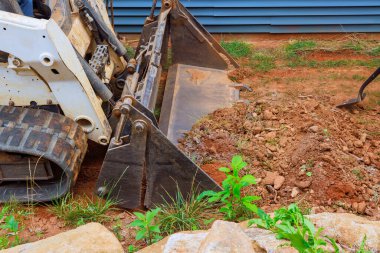 Mini buldozeriyle peyzaj projesinin üstesinden gelerek toprağı manipüle ederek estetik açıdan memnun edici ortamlar yaratıyor..
